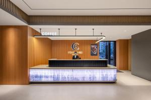 a woman standing at a podium in a hotel lobby at 枫渡酒店上海陆家嘴世纪大道地铁站店 in Shanghai