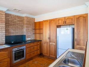 a kitchen with wooden cabinets and a white refrigerator at Rennies Beach Escape "Carinya" in Ulladulla