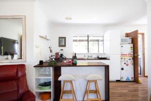 a kitchen with a counter and two bar stools at Sandy's Beach Shack at Bawley in Bawley Point