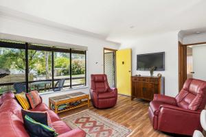 a living room with a couch and two chairs and a television at Sandy's Beach Shack at Bawley in Bawley Point