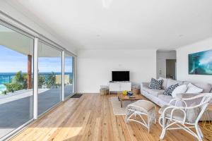 a living room with a couch and a large window at Ocean Overlook - Rennies Beach holiday haven in Ulladulla