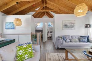 a living room with white furniture and wooden ceilings at The Beach Haven in Bawley Point