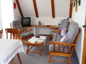 sala de estar con sillas, mesa y TV en Ferienhaus im Grund, en Hinterzarten