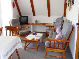 ein Wohnzimmer mit Stühlen, einem Tisch und einem TV in der Unterkunft Ferienhaus im Grund in Hinterzarten