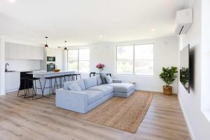 a white living room with a couch and a kitchen at Mollymook Delight - with easy ocean & golf access in Mollymook