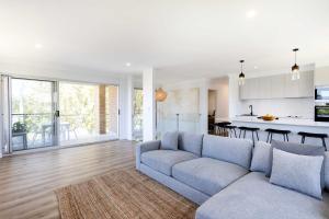 a living room with a couch and a kitchen at Mollymook Delight - with easy ocean & golf access in Mollymook