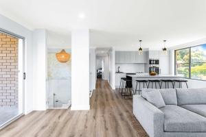 a living room with a couch and a kitchen at Mollymook Delight - with easy ocean & golf access in Mollymook