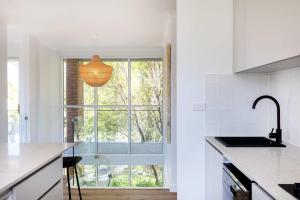 a white kitchen with a large window and a sink at Mollymook Delight - with easy ocean & golf access in Mollymook
