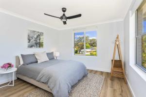 a bedroom with a bed and a ceiling fan at Mollymook Delight - with easy ocean & golf access in Mollymook +19 photos