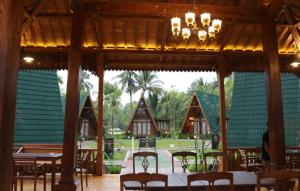 a dining room with tables and chairs and a chandelier at Balkondes Saka Pitu in Kembanglimus +1 photo