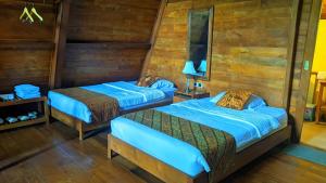 two beds in a room with wooden walls at Balkondes Saka Pitu in Kembanglimus