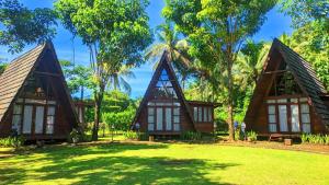 a resort with two thatched cottages in the trees at Balkondes Saka Pitu in Kembanglimus