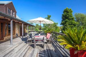 a wooden deck with a table and an umbrella at Stone Cottage - vineyard estate w. fireplace in Milton +18 photos