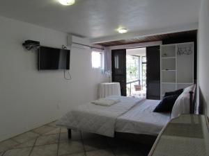 1 dormitorio con 1 cama y TV en la pared en Caixa D'aço Residence, en Porto Belo