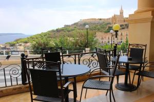 a group of tables and chairs on a balcony with a view at Grand Hotel Gozo in Għajnsielem