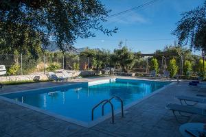 a swimming pool with blue water in a yard at Io in Stoupa