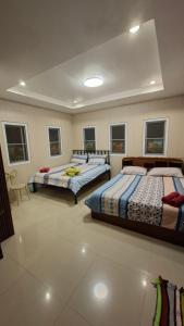 two beds in a large room with windows at บ้านแสงเพ็ญ by แช่มช้อย in Ban Khao Ya Nua