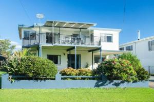 a white house with a balcony and bushes at MeNo's at Bawley in Bawley Point