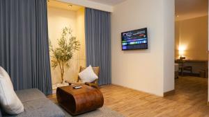 a living room with a couch and a tv on a wall at The Rivavi Legian in Legian