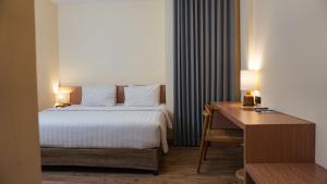 a hotel room with a bed and a desk and a bed sidx sidx sidx sidx at The Rivavi Legian in Legian