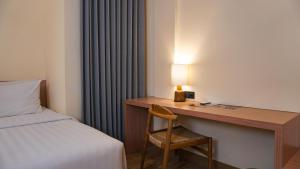 a hotel room with a desk with a bed and a lamp at The Rivavi Legian in Legian +12 photos