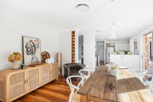 a dining room with a wooden table and white chairs at Point Break in Bawley Point