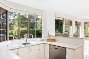 a white kitchen with windows and a sink at Point Break in Bawley Point +17 photos