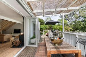 a deck with a wooden table and an umbrella at Coastal Soul in Narrawallee
