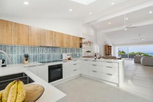 a kitchen with white cabinets and bananas on a counter at Thalassa Views Ulladulla in Ulladulla