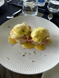 a white plate with eggs and potatoes on a table at Candella House in Talpe