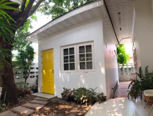 a small white house with a yellow door at Homestay Laksi in Lak Si