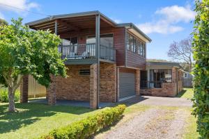 a brick house with a balcony and a tree at Barker Retreat in Burrill Lake +18 photos