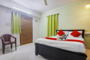 a bedroom with a large bed and a chair at Hotel O RR in Kondapur