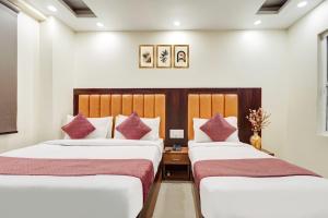 two beds in a hotel room with white and purple pillows at Hotel Aerotech Near Delhi Airport in New Delhi