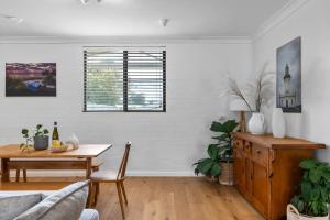 a living room with a table and a couch and a window at Lilly Pilly at Callala Beach in Callala Beach