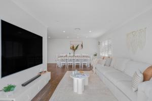 a white living room with a large flat screen tv at Sanctuary Splash Getaway in Sanctuary Point
