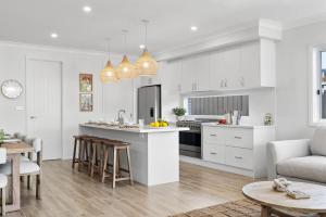 a kitchen and living room with white cabinets at Mare Mio Callala Beach Jervis Bay in Callala Beach