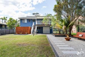 a yard with a blue house and a bench at Kangaroo Sanctuary Studio in Sanctuary Point