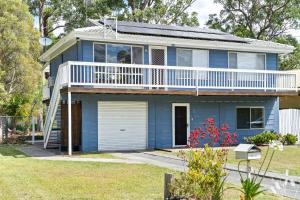 a blue house with a balcony and a yard at Kangaroo Sanctuary Studio in Sanctuary Point
