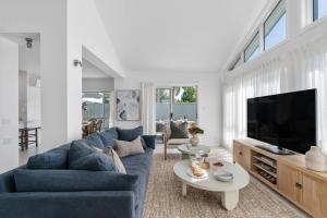 a living room with a blue couch and a tv at Husky Salt in Huskisson