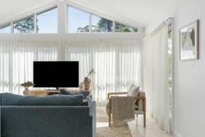 a living room with a blue couch and a tv at Husky Salt in Huskisson
