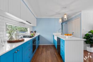 a blue and white kitchen with white counters and blue cabinets at Kangaroo Sanctuary in Sanctuary Point