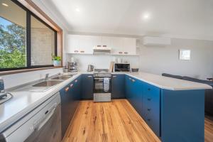 a kitchen with blue cabinets and a wooden floor at Sea Stroll at Callala Beach in Callala Beach