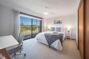 a bedroom with a bed and a desk and a window at Sea Stroll at Callala Beach in Callala Beach