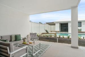 a patio with a couch and chairs and a pool at Beachside on Beecroft in Huskisson