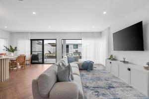a living room with a couch and a flat screen tv at Beachside on Beecroft in Huskisson