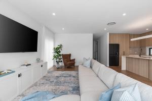 a living room with a white couch and a tv at Beachside on Beecroft in Huskisson +29 photos