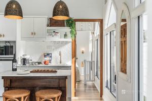 a kitchen with white cabinets and a counter with stools at Chapel by the Bay in Erowal Bay