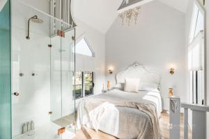 a white bedroom with a bed and a glass shower at Chapel by the Bay in Erowal Bay