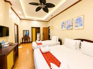 a hotel room with two beds and a flat screen tv at Villa Khili Phousi in Luang Prabang
